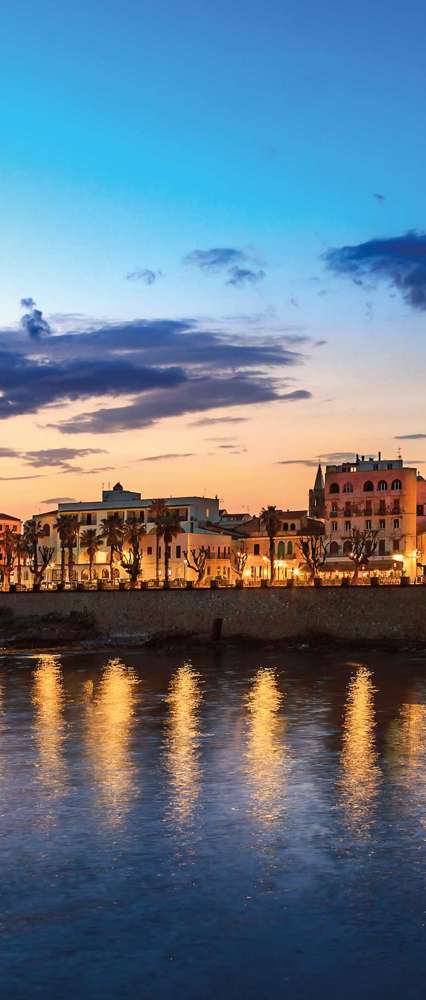 Night view of Alghero Torre Di Sulis from the water, Italy