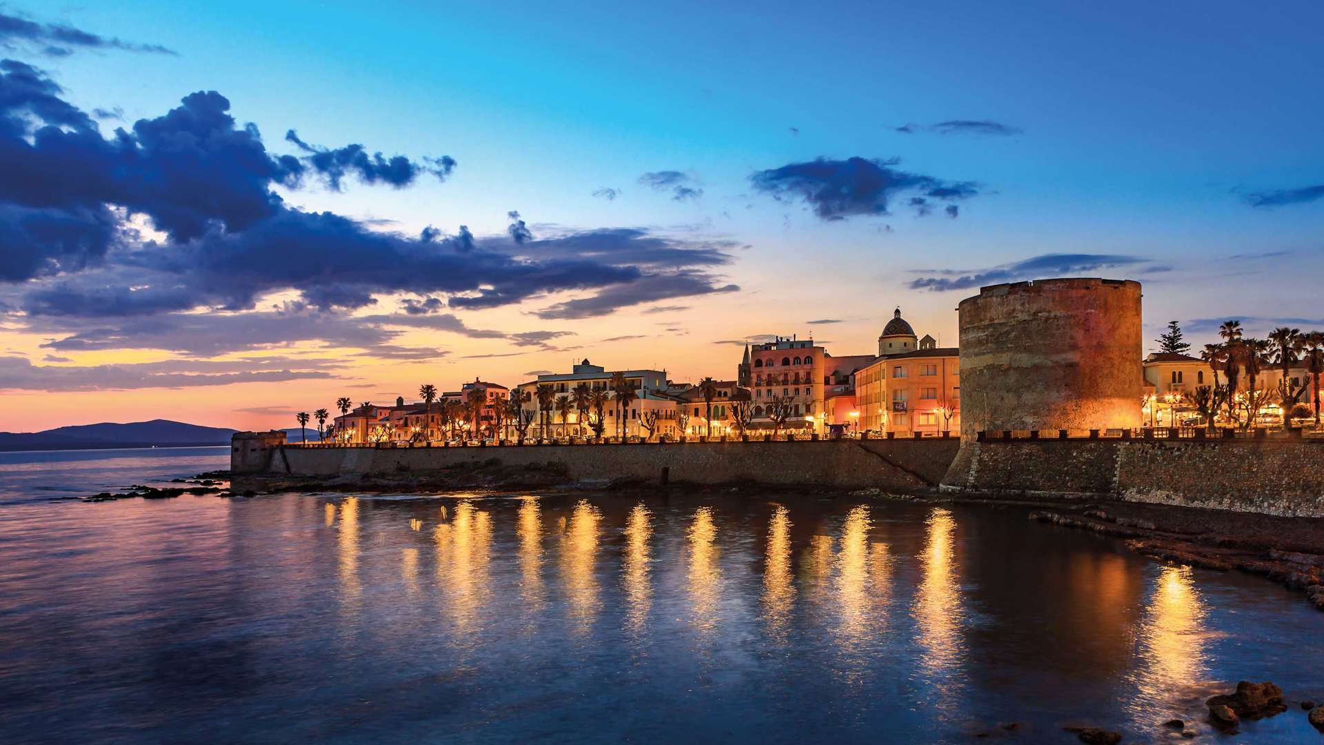 Night view of Alghero Torre Di Sulis from the water, Italy