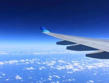 View of aeroplane wing in the sky over clouds