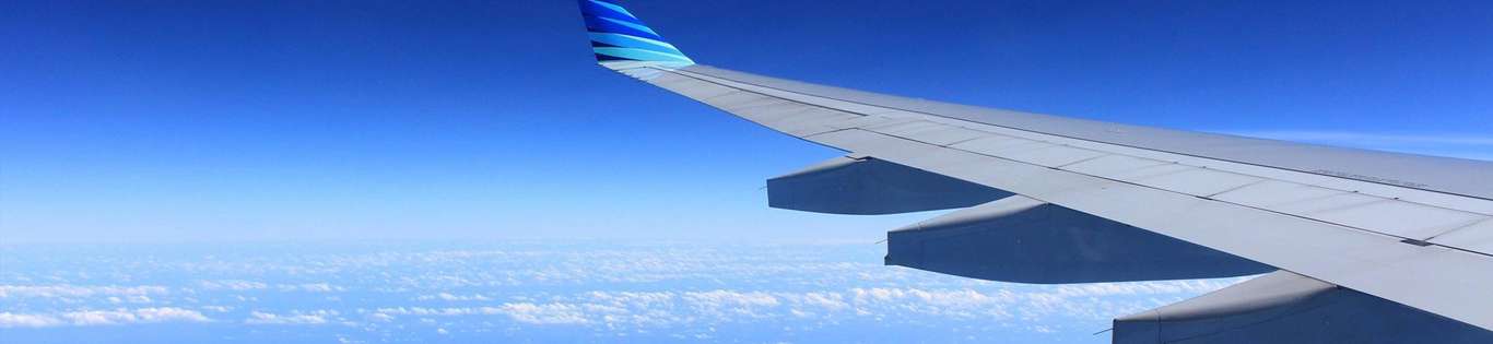 View of aeroplane wing in the sky over clouds