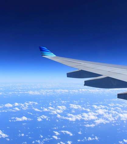 View of aeroplane wing in the sky over clouds