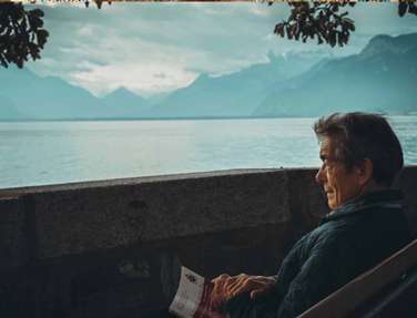 Ma sitting on a lounger with a book folded in his hands looking out over water