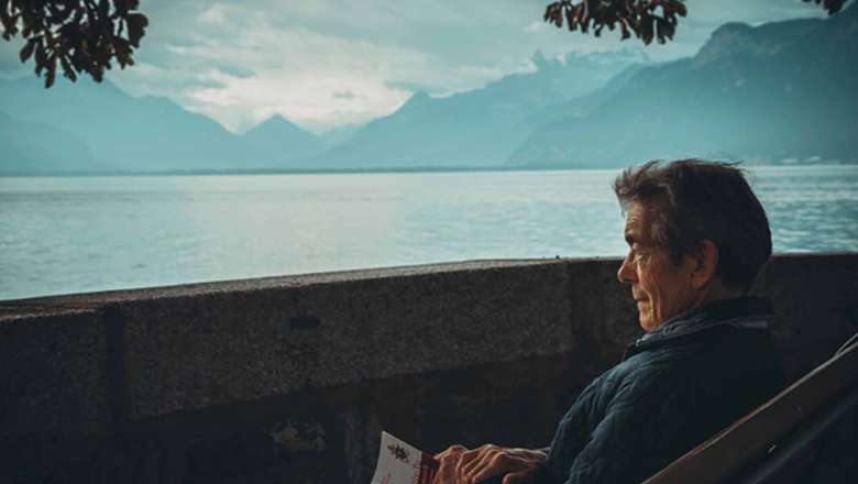 Ma sitting on a lounger with a book folded in his hands looking out over water