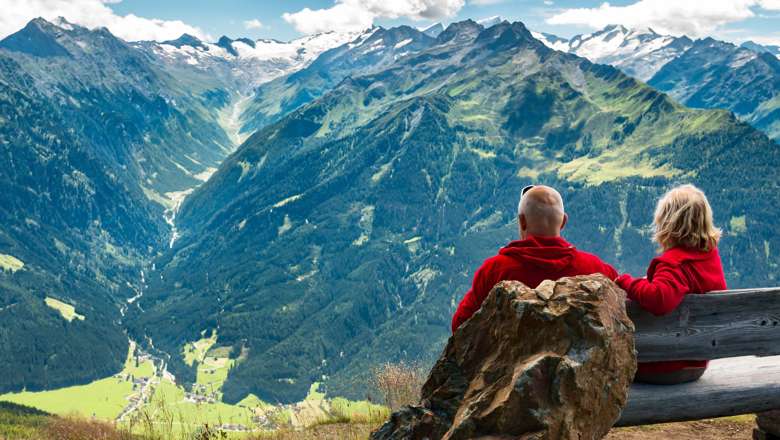 Couple sitting on bench overlooking mountains