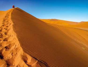 Tourist walking up a dune, Sossusvlei, Namib Nukluft National Park, Namibia