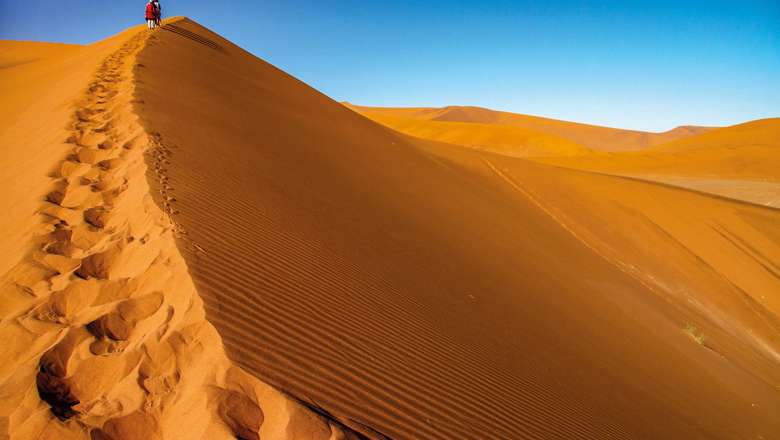 Tourist walking up a dune, Sossusvlei, Namib Nukluft National Park, Namibia