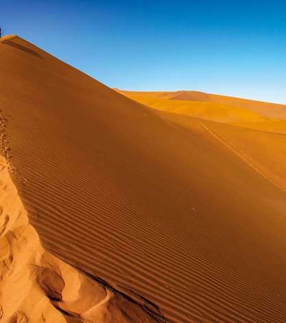 Tourist walking up a dune, Sossusvlei, Namib Nukluft National Park, Namibia