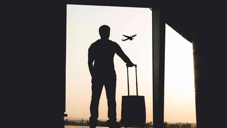 Man standing in airport watching plane leave